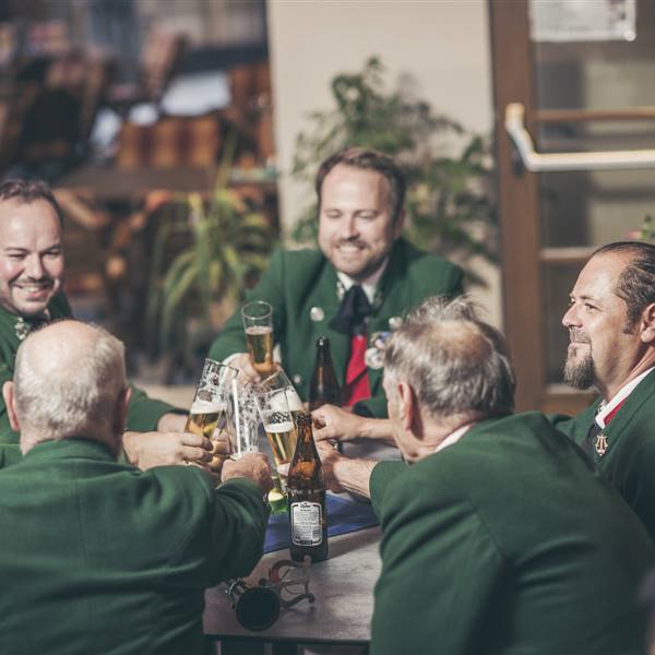 Musikanten prosten sich mit Bier in einem Wirtshaus zu