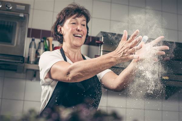 Frau steht in der Küche mit Mehl an den Händen